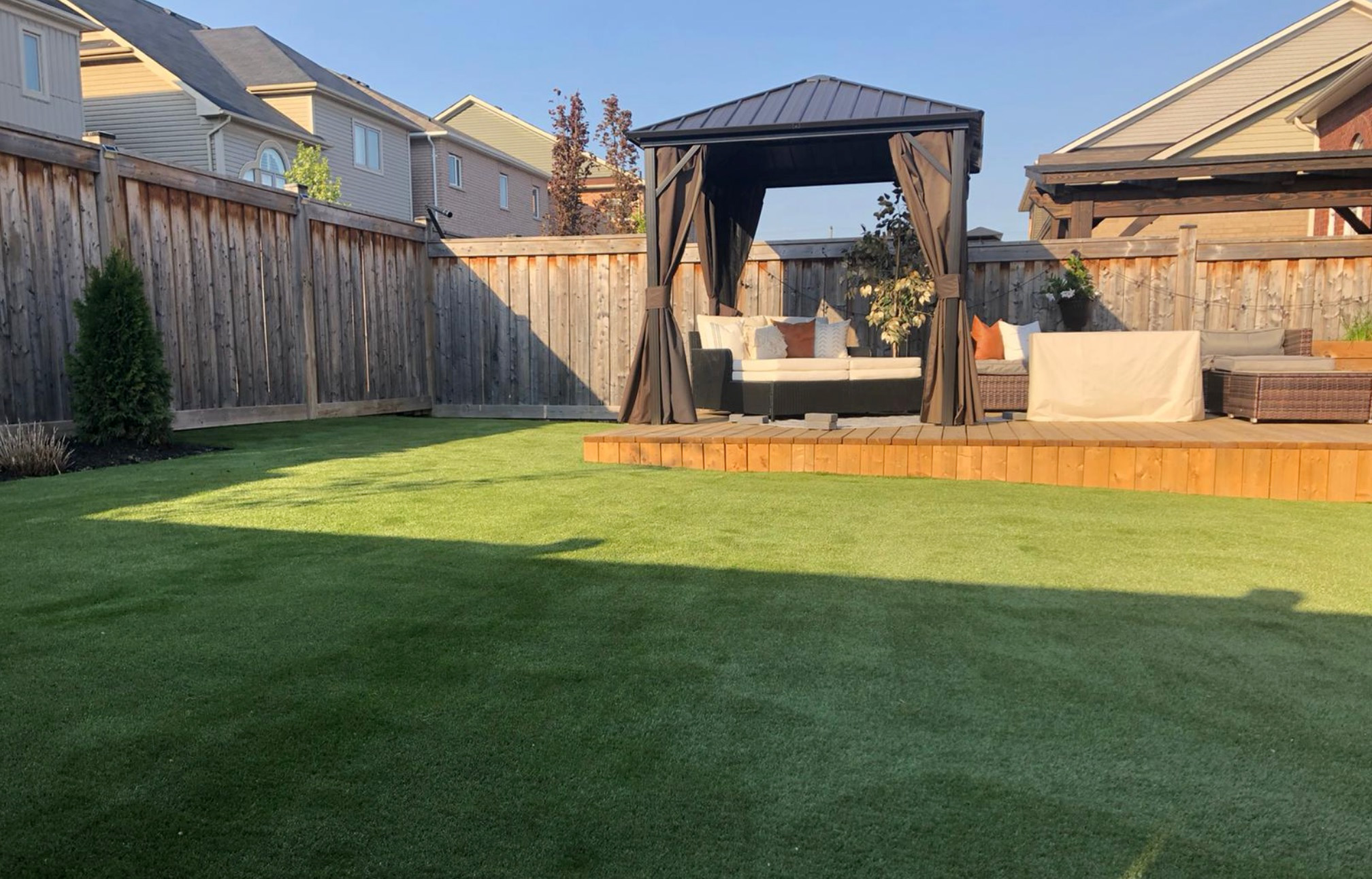 artificial grass installed around wooden deck in backyard